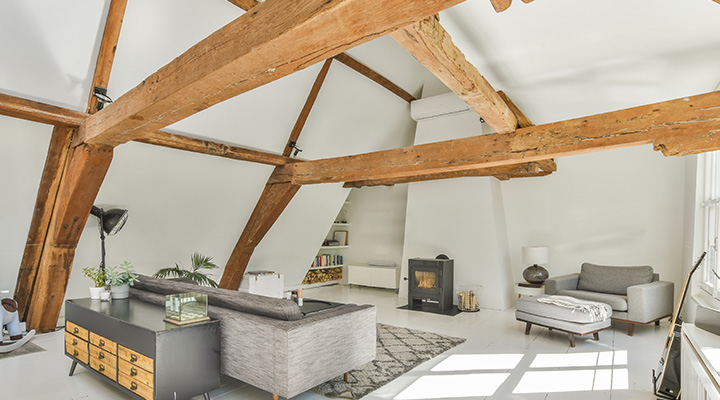 spacious living room featuring wooden beams and modern furniture with cozy fireplace ideal for two people