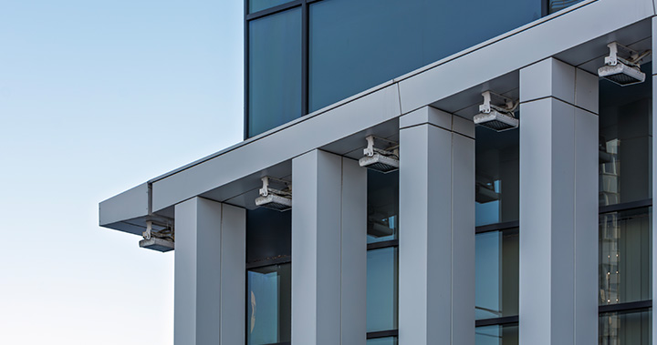 modern building facade with glass and metal design showcasing two rows of columns and security lights