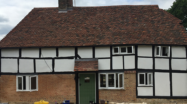 traditional English cottage with exposed timber framing and a green front door, showcasing a rustic design that highlights historical architecture and charm, ideal for two-story homes