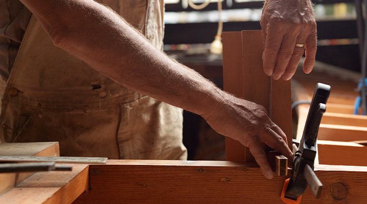 construction site with two unfinished stone pillars being installed on a building foundation with workers and scaffolding in the background