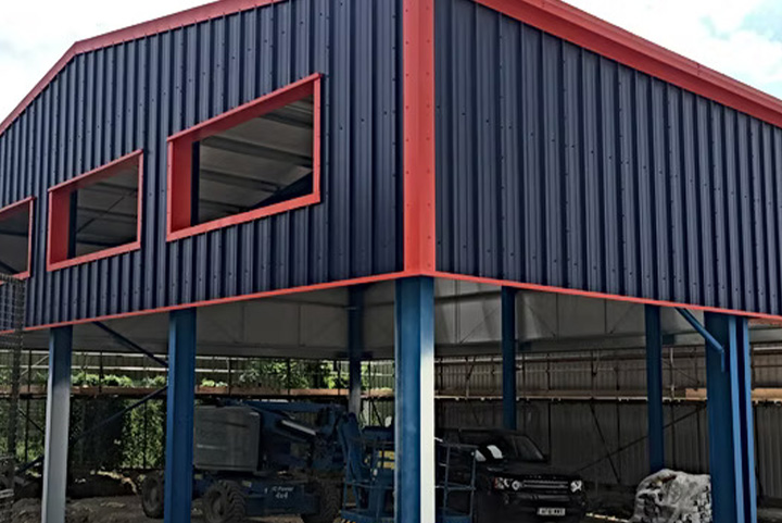 steel framed building with red trim featuring large windows construction site visible equipment three structural details